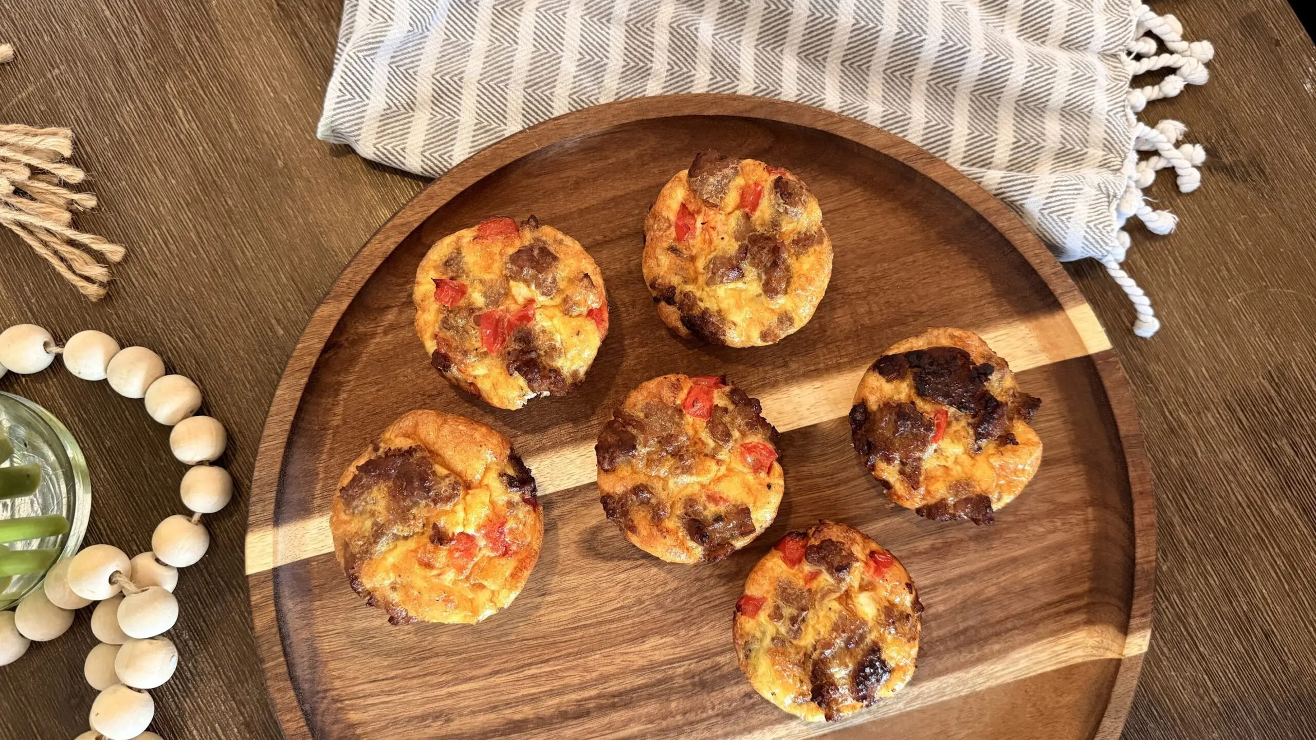 A plate of cheesy egg cups on a wooden platter.
