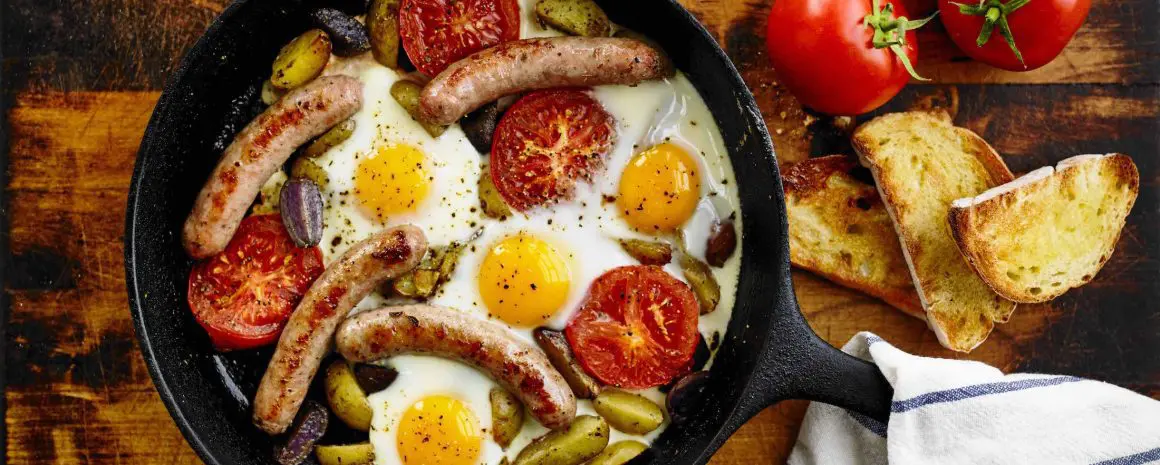 A pan of eggs breakfast sausages and veggies.