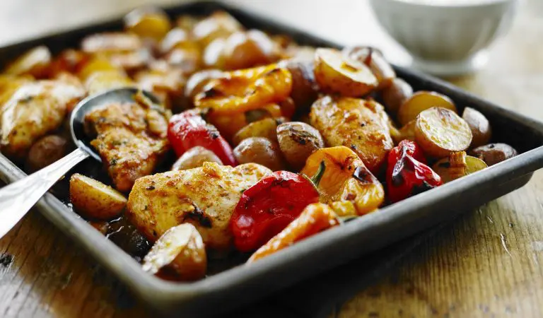 Poulet jerk rôti sur une plaque avec petites pommes de terre et poivrons