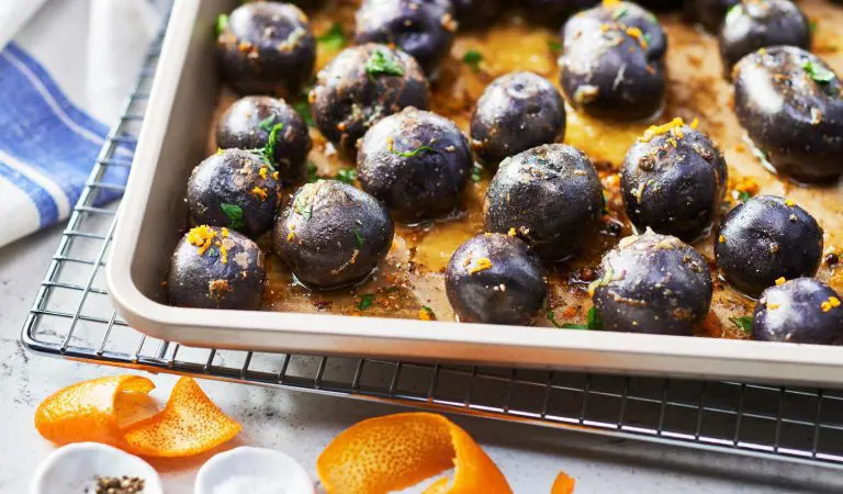 Purple potatoes with some orange zest on a roasting tray.