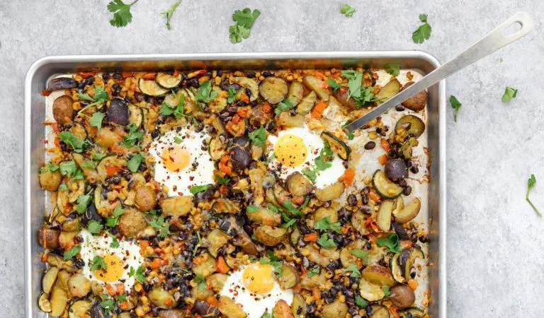 Déjeuner style hash sur plaque avec petites pommes de terre, œufs et légumes