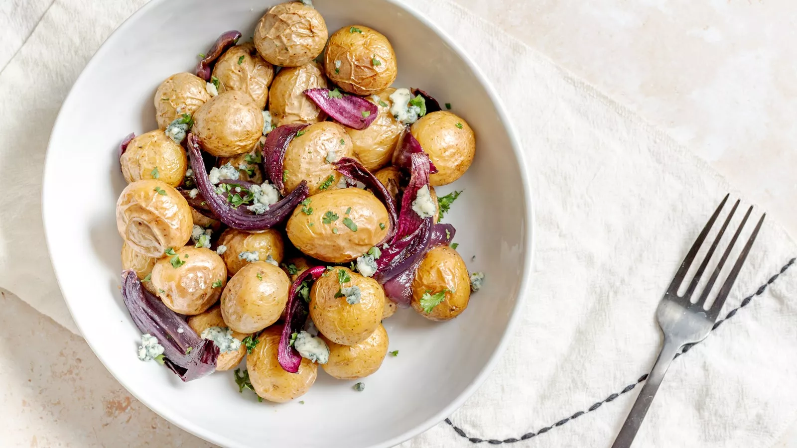 A plate of roasted potatoes and onions with blue cheese.