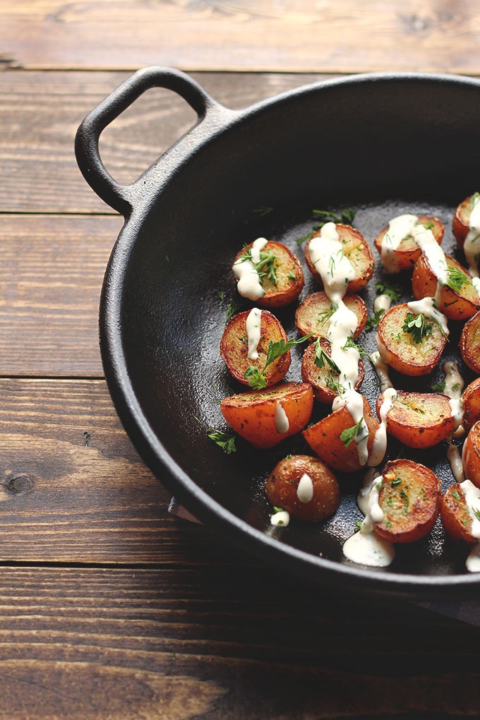 Crispy potatoes with vegan ranch dressing in a skillet.