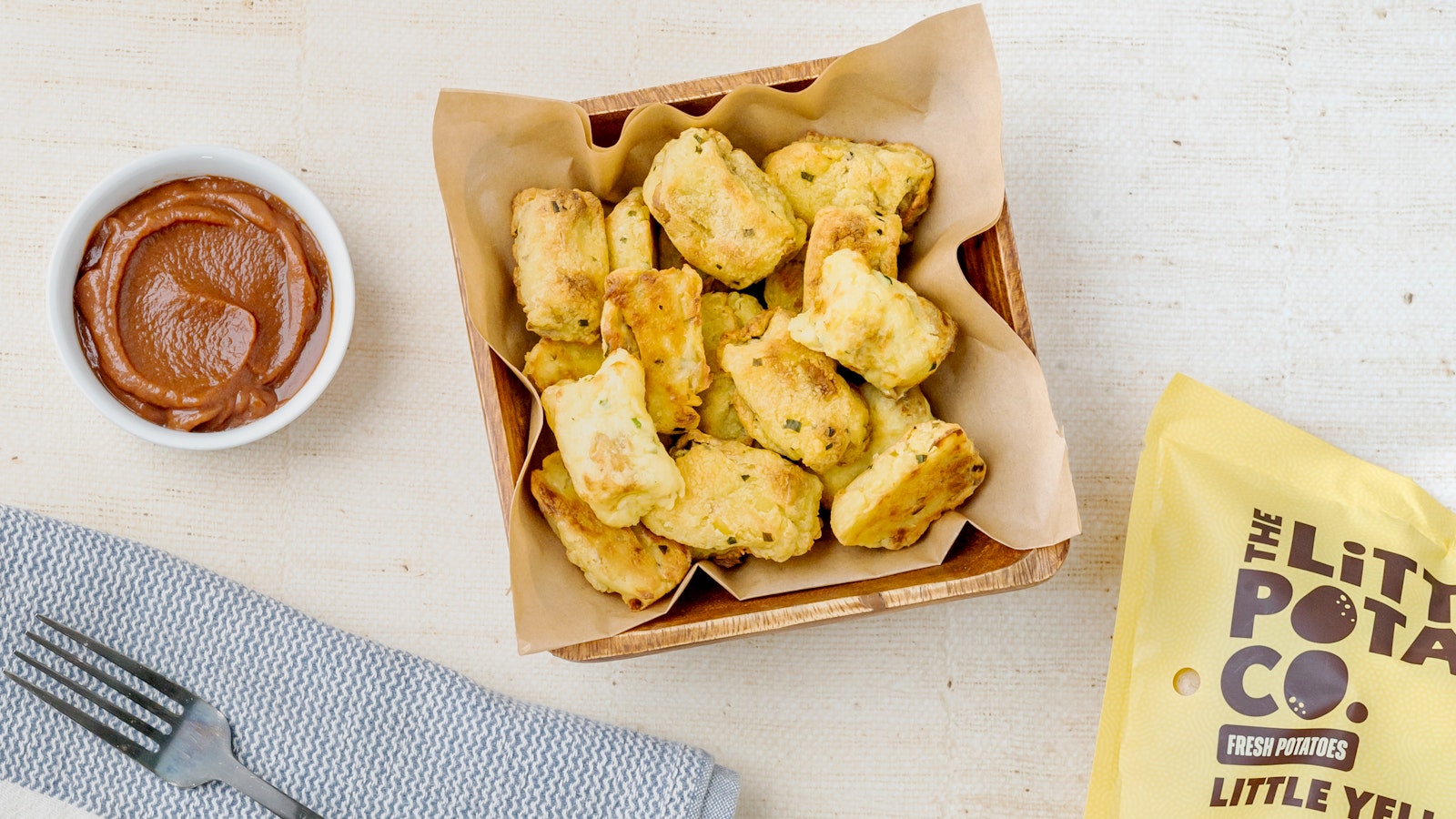 A plate of healthy baked herb and garlic tater tots next to a bag of Little Yellows®