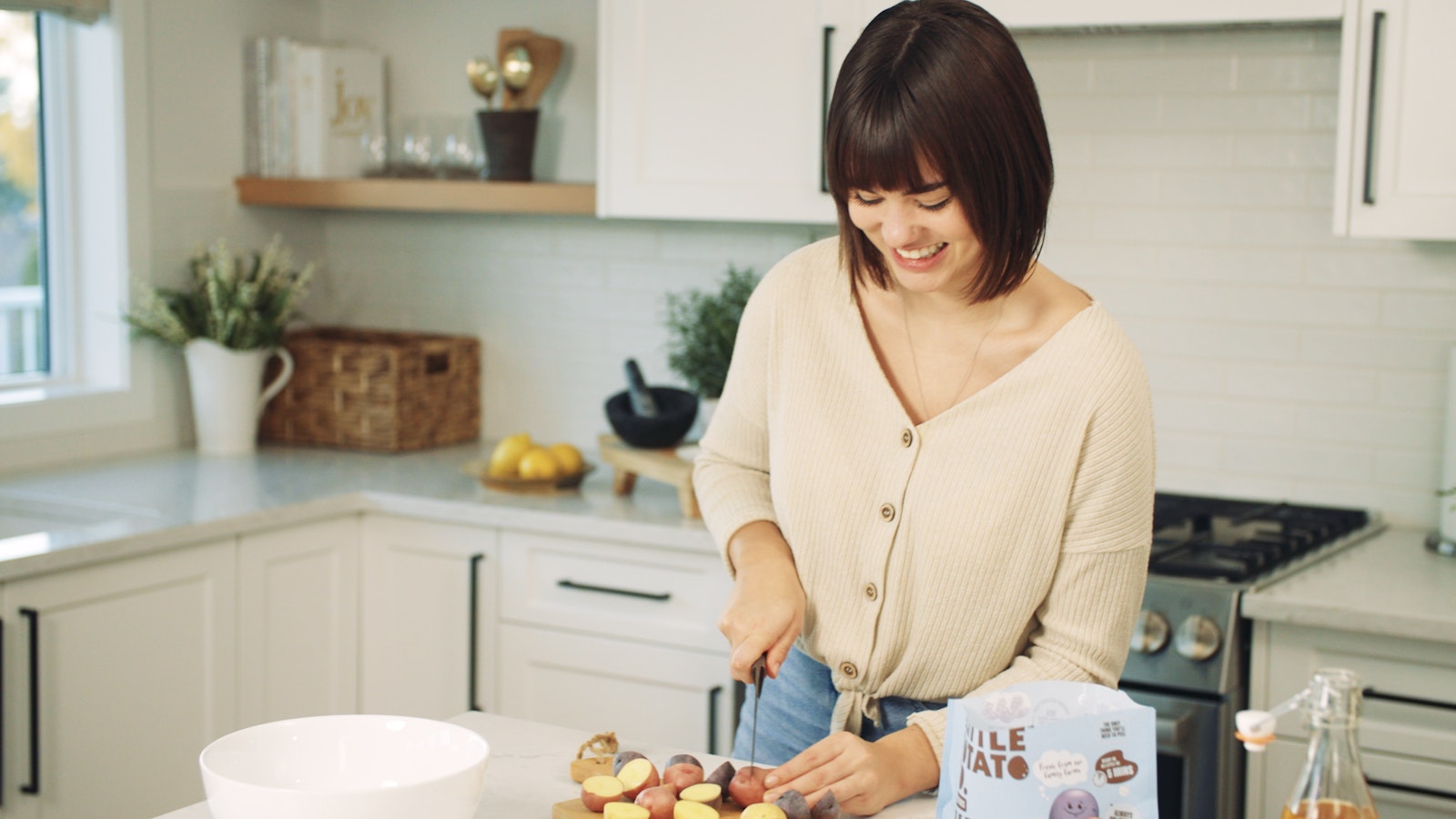 A woman in the kitchen chopping up some Little Potatoes.