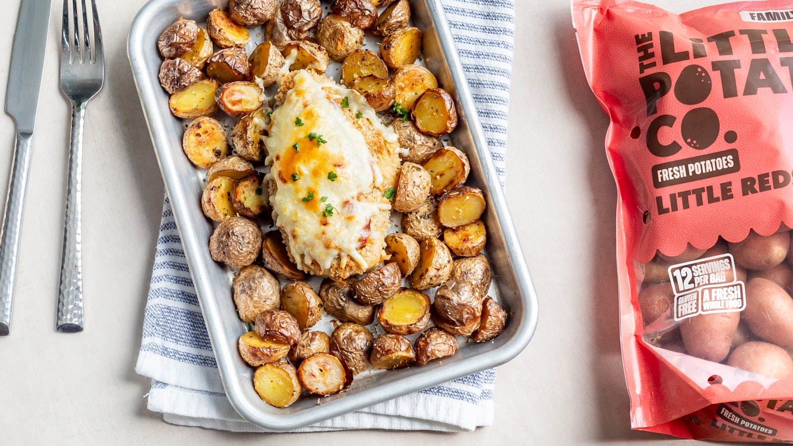 A sheet pan with chicken parm on top of a bed of Little Reds™
