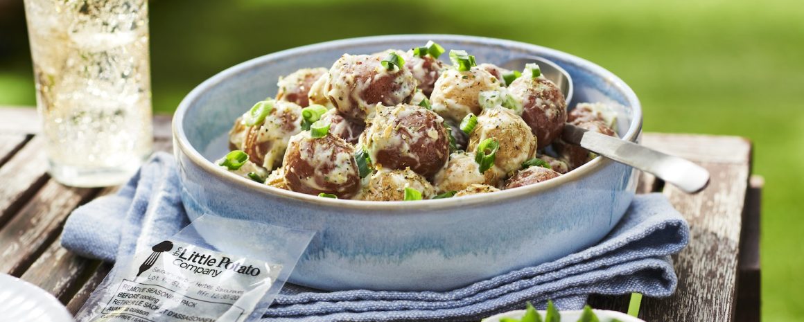 An easy to make potato salad in a blue bowl with a refreshing drink nearby.