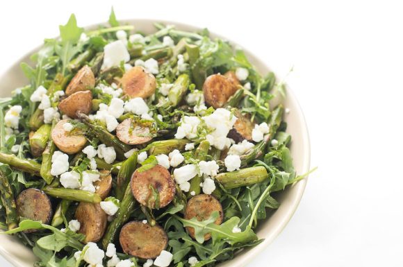 An arugula salad with roasted potatoes and goat cheese.