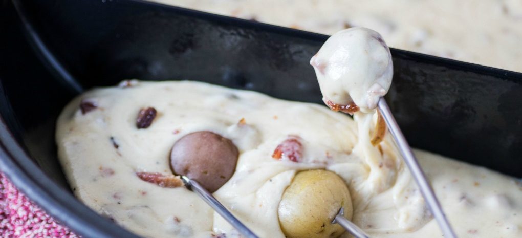 A bowl of fondue with little potatoes.