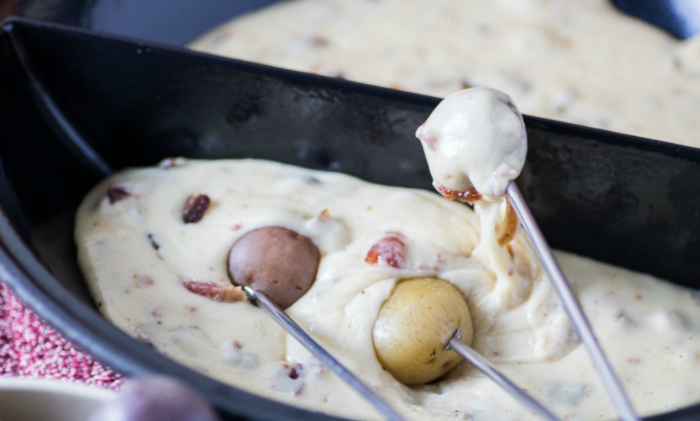 A bowl of fondue with little potatoes.