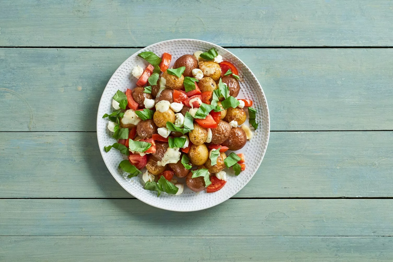 A beautiful colorful bowl of caprese roasted little potatoes.