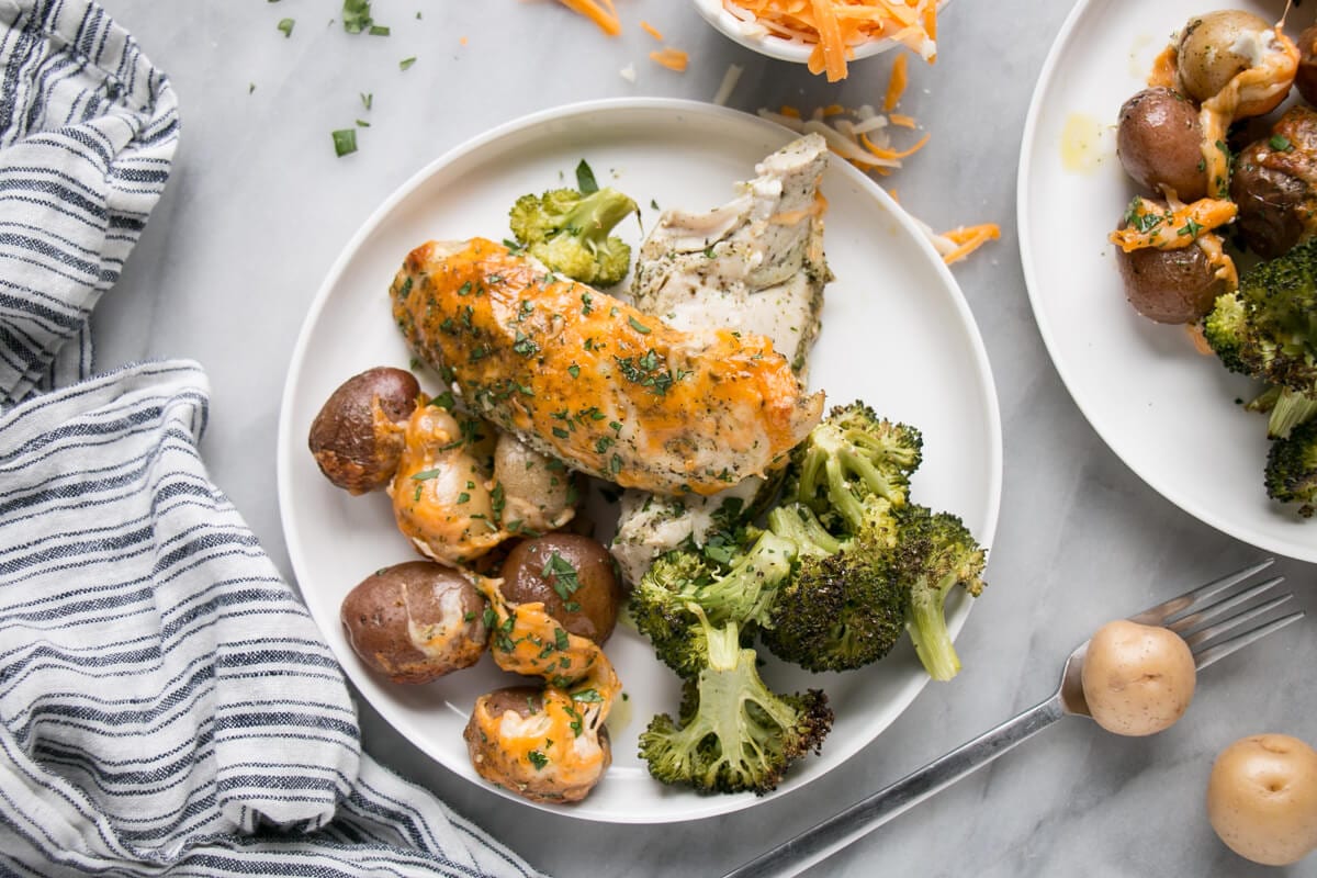 Cheesy chicken and potatoes with broccoli on a plate.