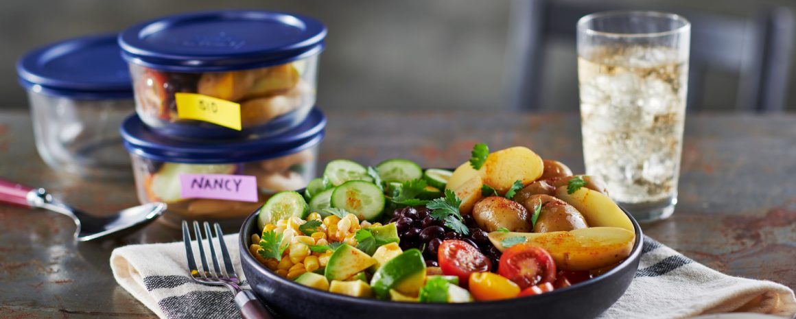 A bowl of fresh delicious salad with potatoes on top.