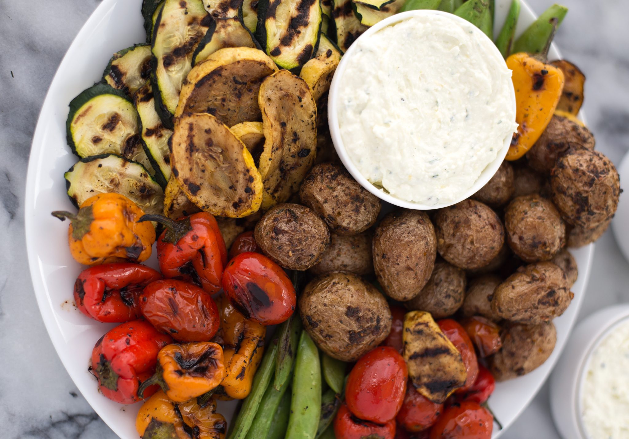 A platter of grilled veggies with some lemon feta dip