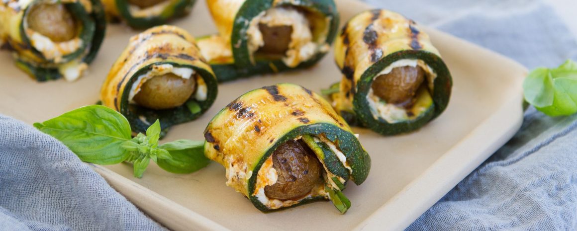 A plate of grilled little potatoes wrapped in grilled zucchini.