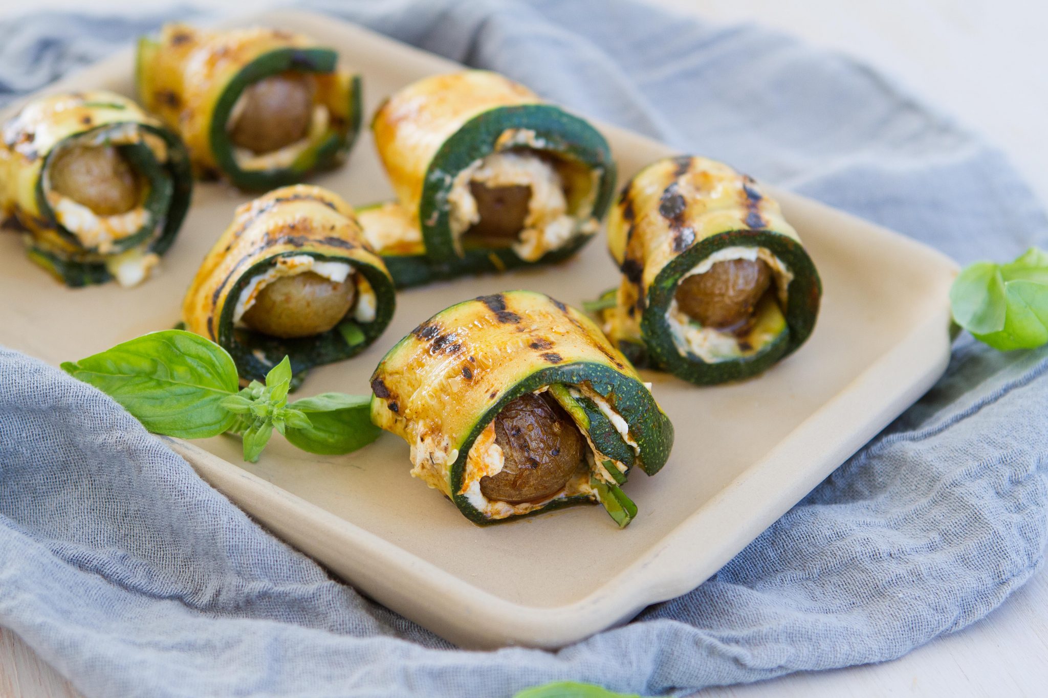 A plate of grilled little potatoes wrapped in grilled zucchini.