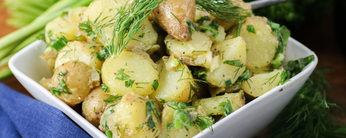 A dish of potato salad with lots of fresh herbs.