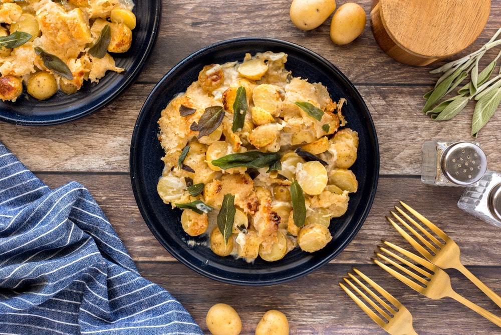 Layers of creamy, cheesy, little potatoes in a bowl topped with sage.