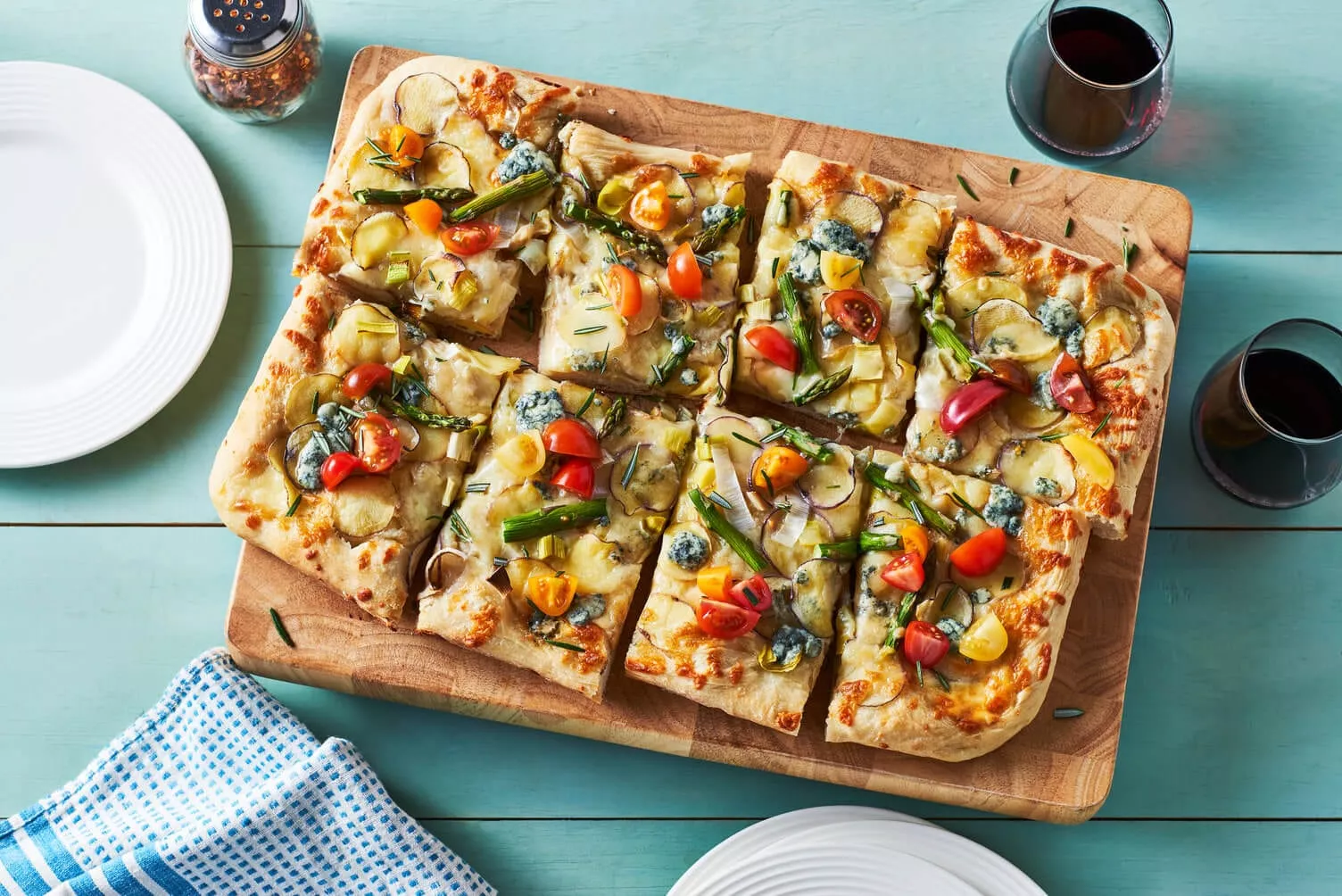 A lovely cutting board with a beautiful array of potato pizza on top.