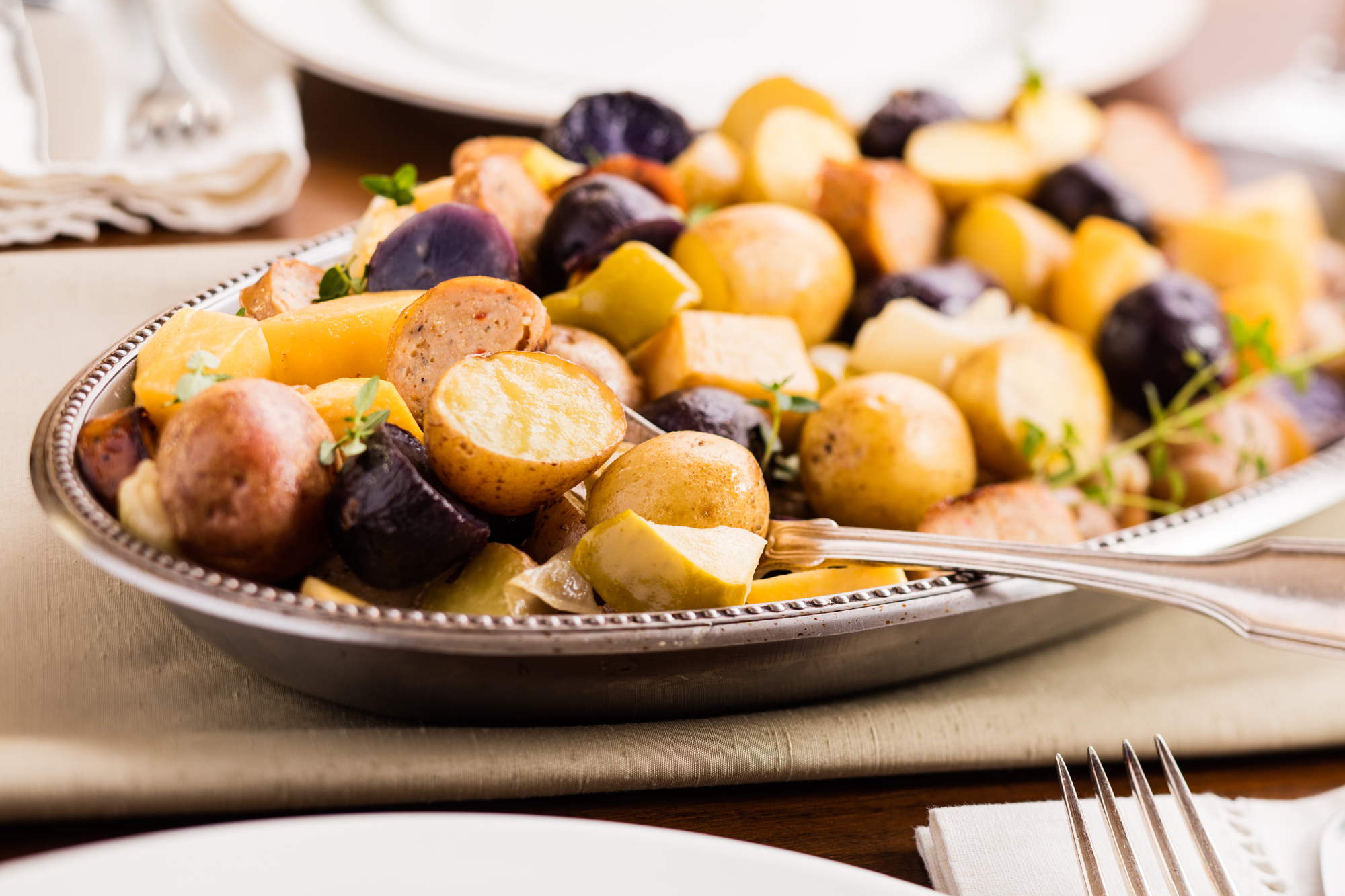 A plate of roasted veggies and sausages.