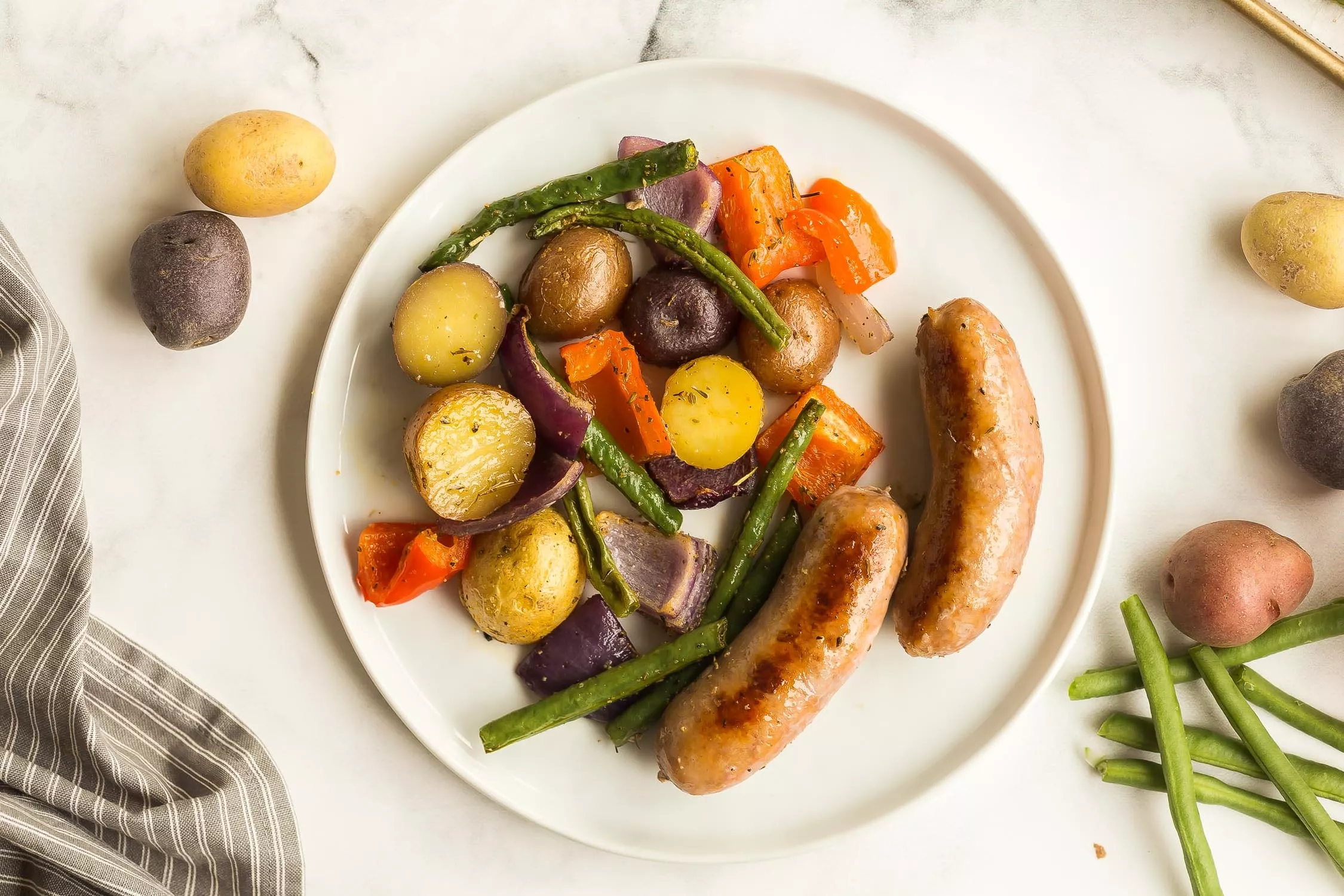 A plate of sheet pan sausages and potatoes.