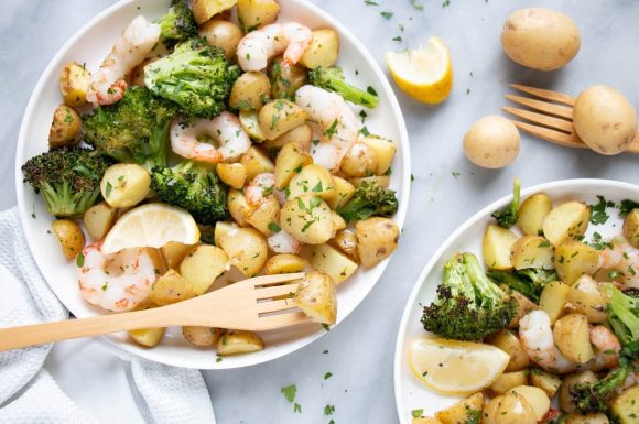 Sheet pan shrimp and potatoes in little plates with cute wooden forks.