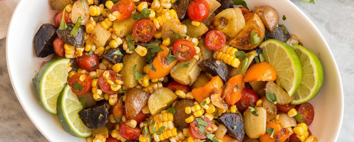 A bowl of southwest potato salad with lots of colorful veggies.