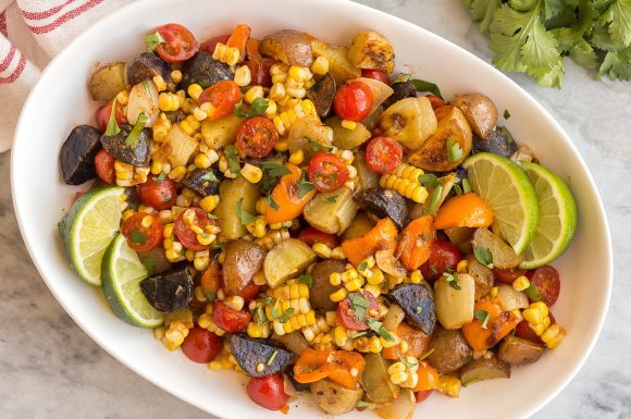 A bowl of southwest potato salad with lots of colorful veggies.