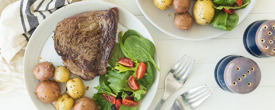 Two plates of steak and potato with salad.
