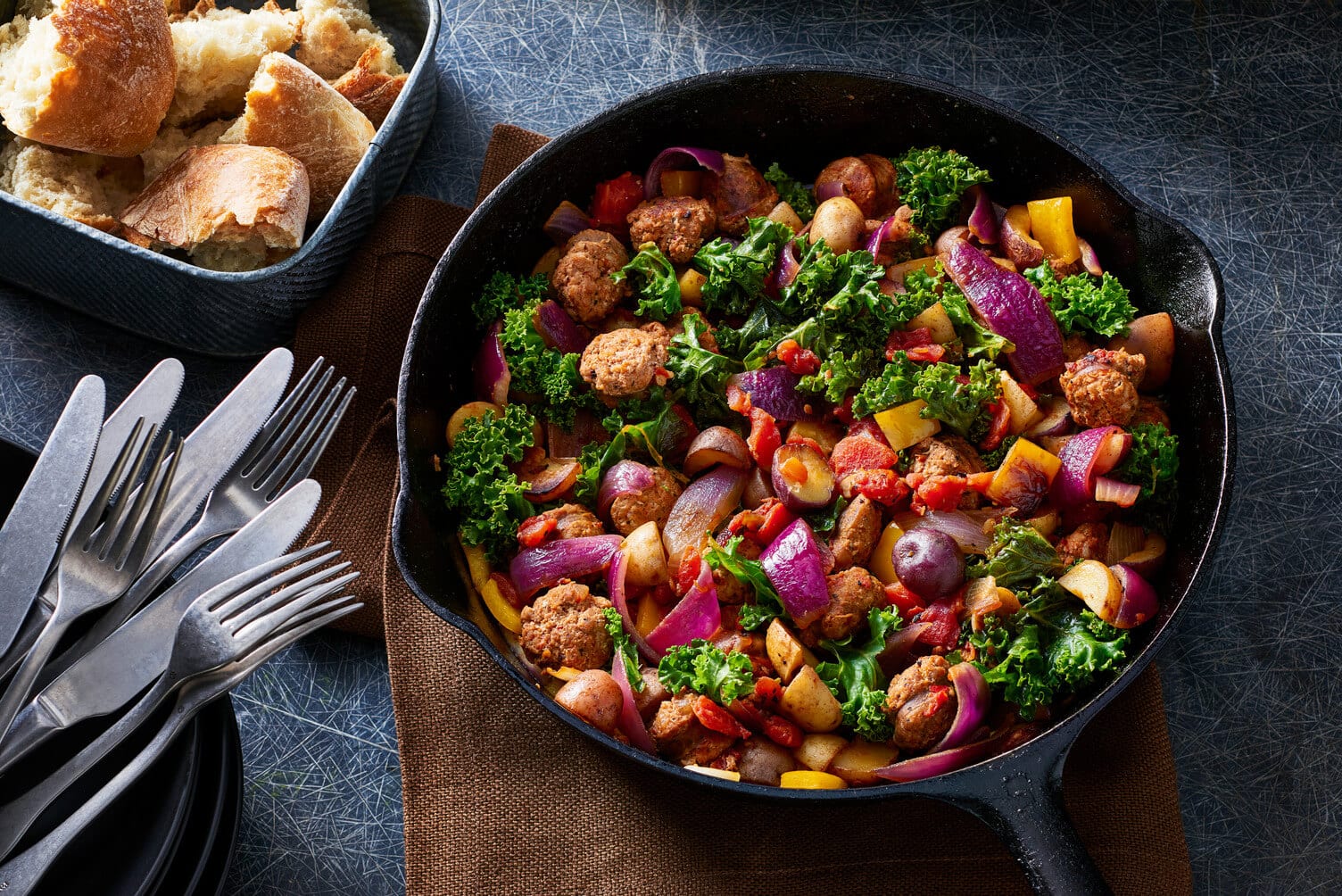 Little Trios™ with kale and sausage in a cast iron skillet.