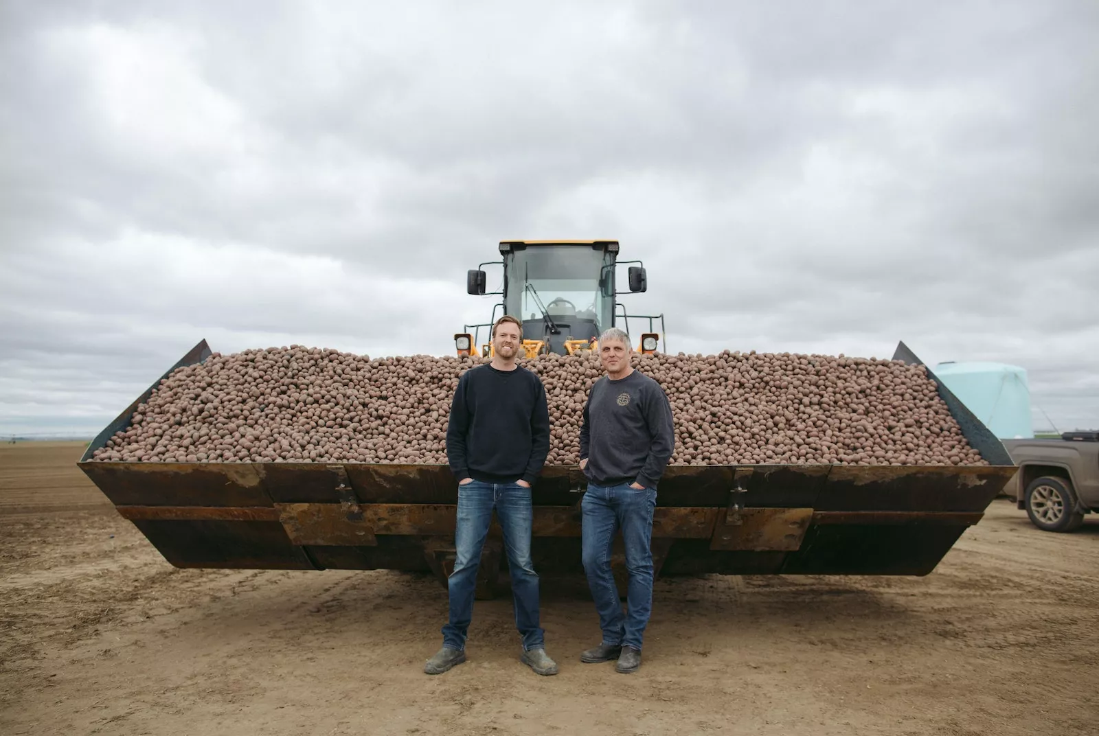 Farmer Profile_Jeroen and Alex Two of our farmers standing in front of a giant tractor of potatoes.