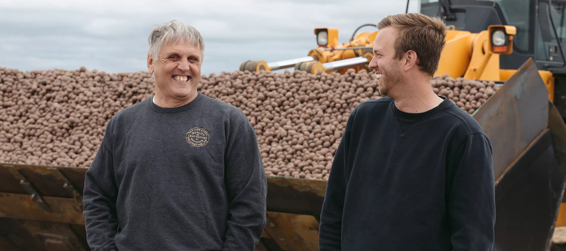 Jeroen and Alex in front of a large pile of potatoes.