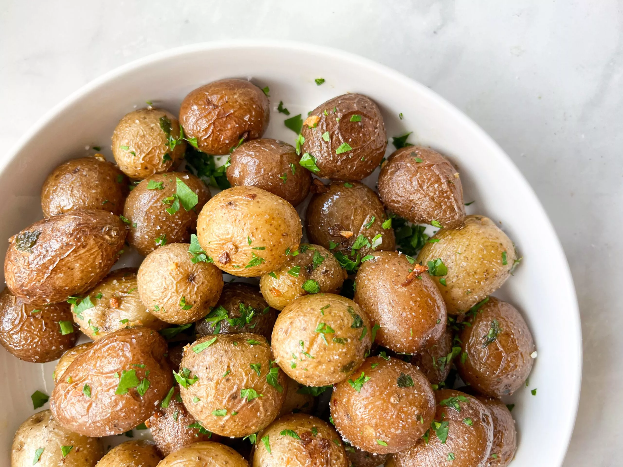 A bowl of Air Fried Little Potatoes with fresh herbs.