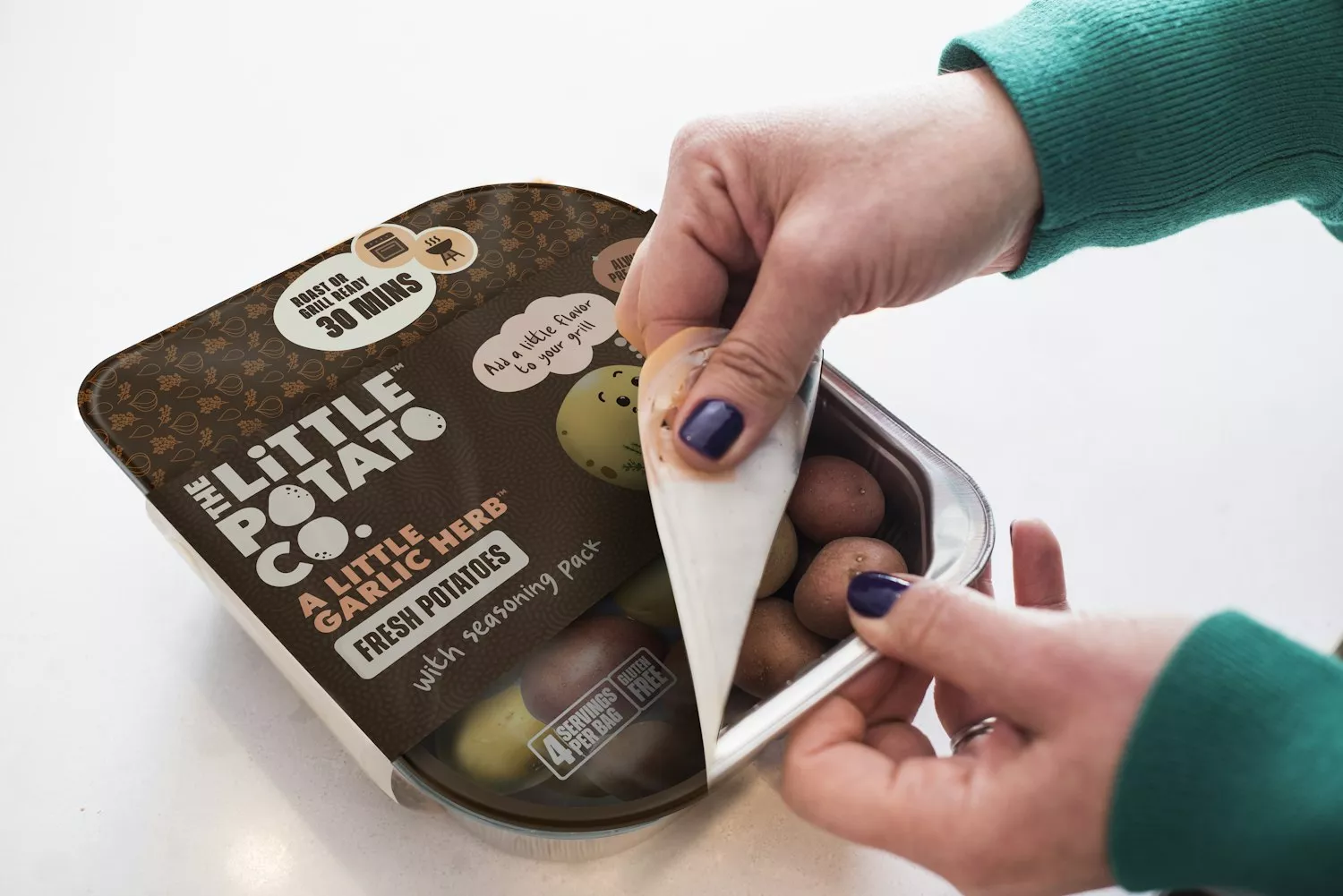 Cheesy Egg and Potato Breakfast Bowls_Liz Della Croce_High Res 1 (1) A hand peeling open a Roast or Grill Ready Little Potatoes package.