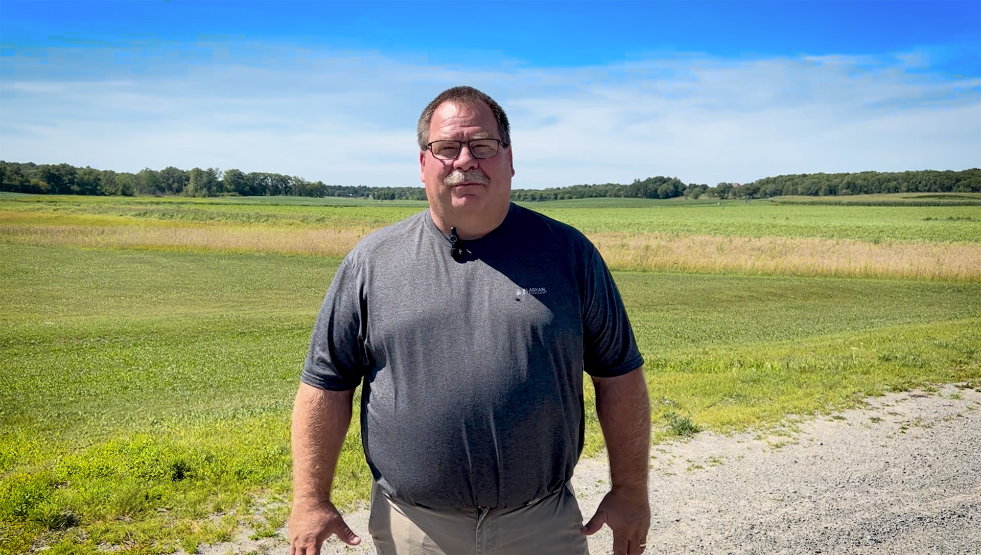 A farmer stands in his field on a nice summer day.