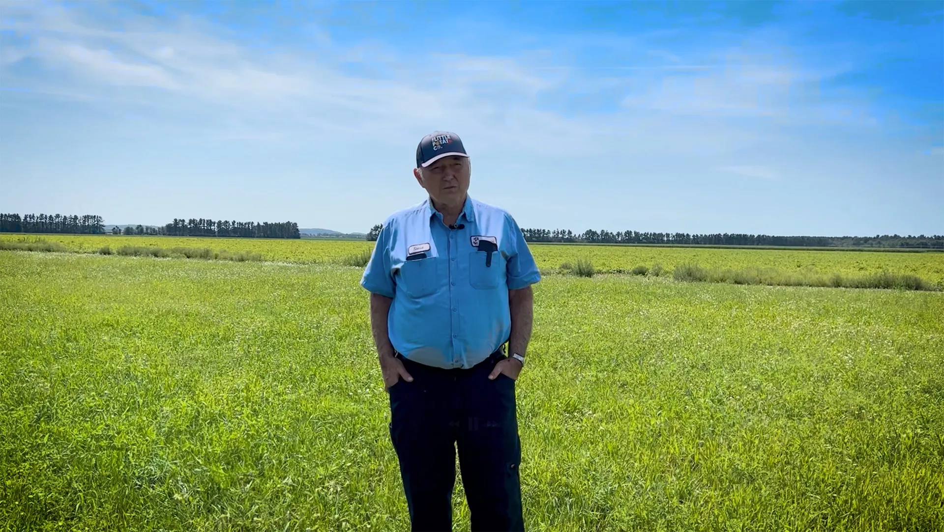 A farmer stands in his field on a lovely summer's day.