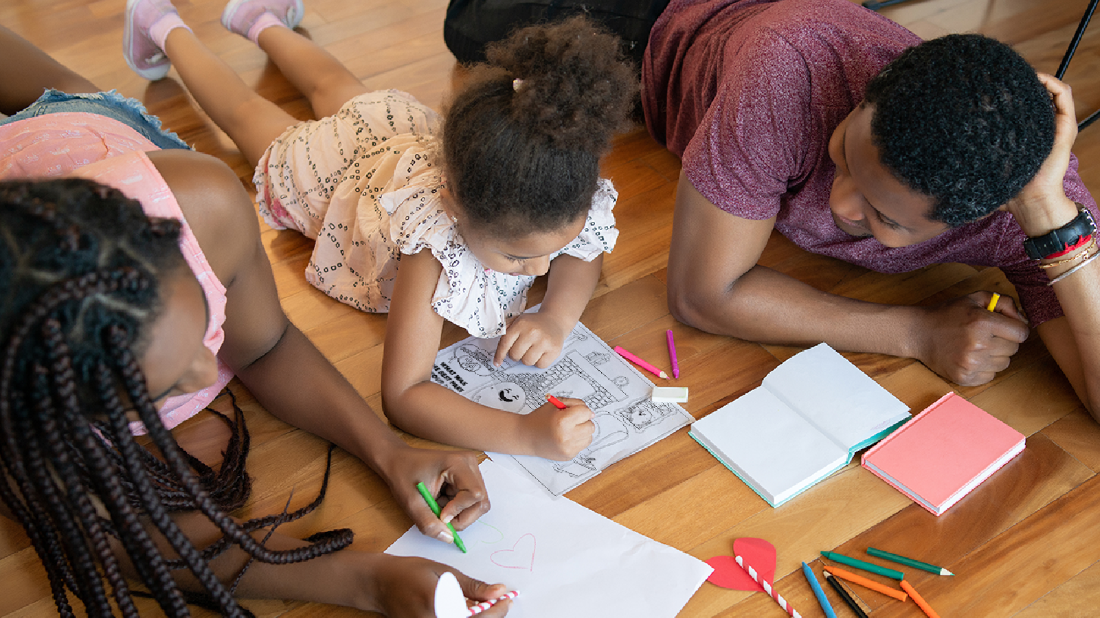 A family gathering around an activity sheet and coloring it in together.