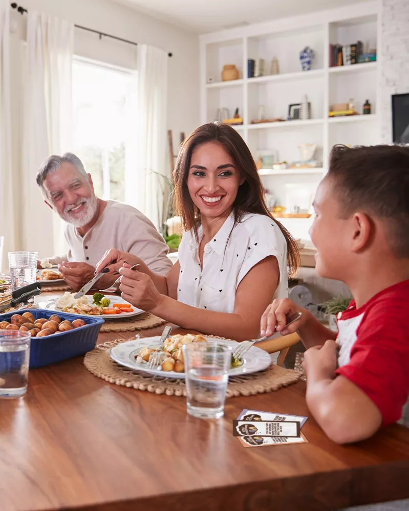 A family sitting around a table reading conversation cards together.