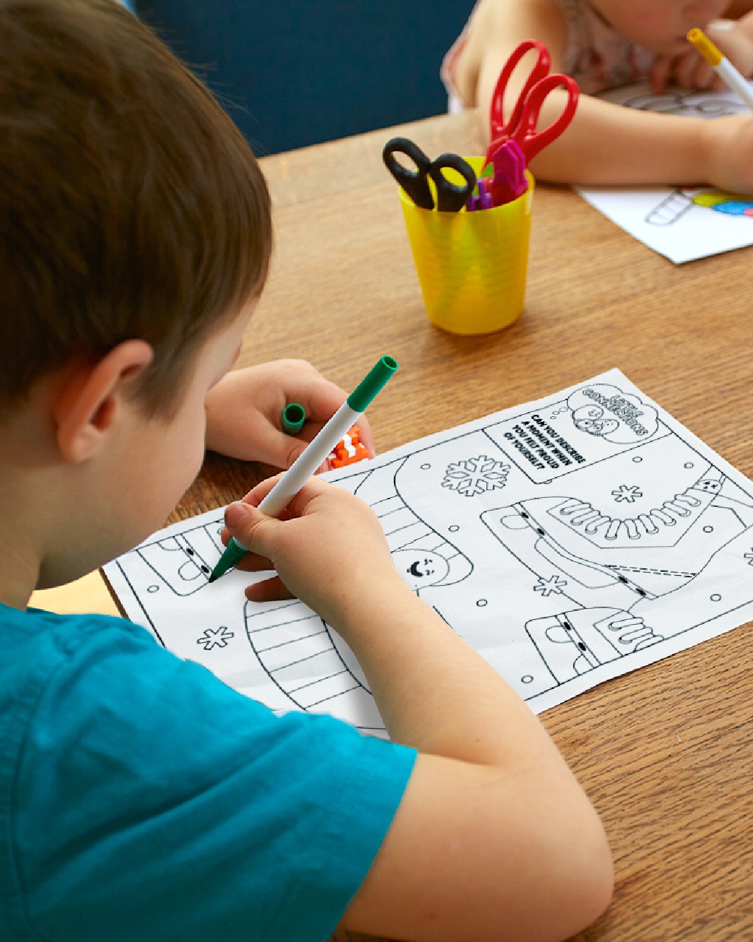 A child colours in a winter themed coloring page.