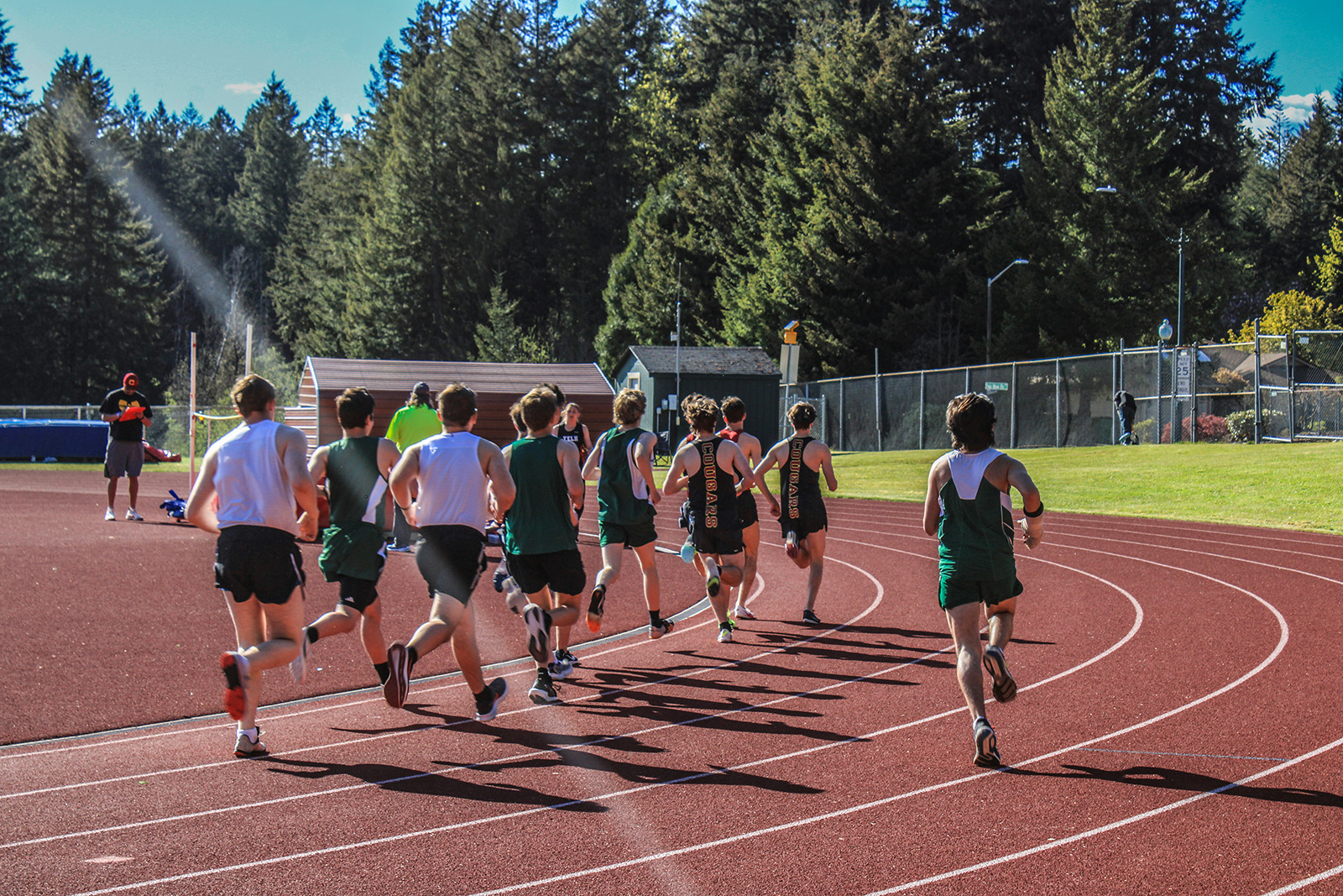 A group of track students run in formation around the circuit.