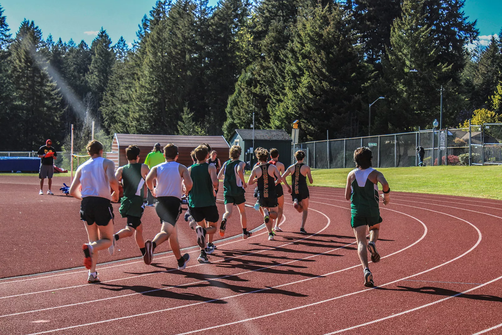 A group of track students run in formation around the circuit.