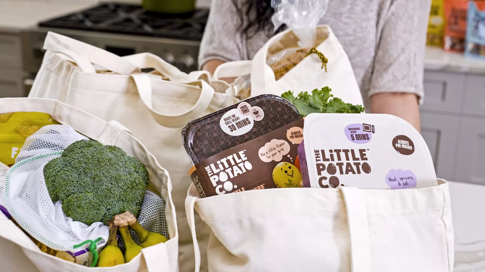 A number of canvas tote bags on the counter featuring delicious Little Potatoes from The Little Potato Company.