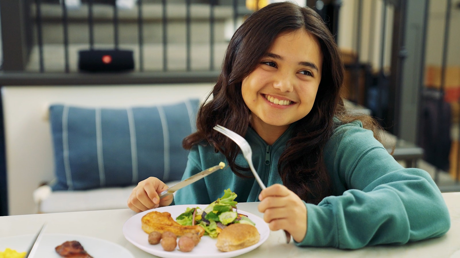 A girl eating her breakfast with a plate full of veggies like Little Yellows™ Little Potatoes.