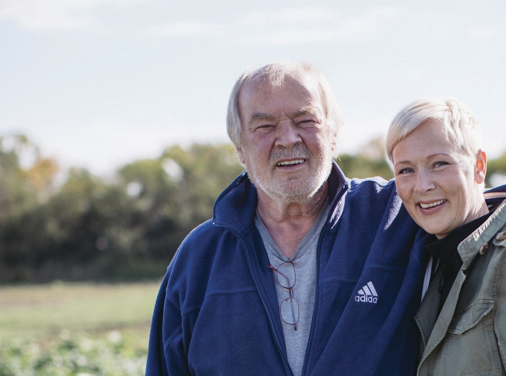 Angela and Jacob standing and smiling in a field.