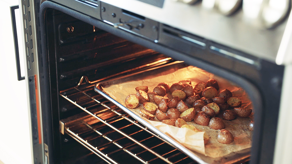A parchment-lined baking sheet of Little Potatoes in the oven.