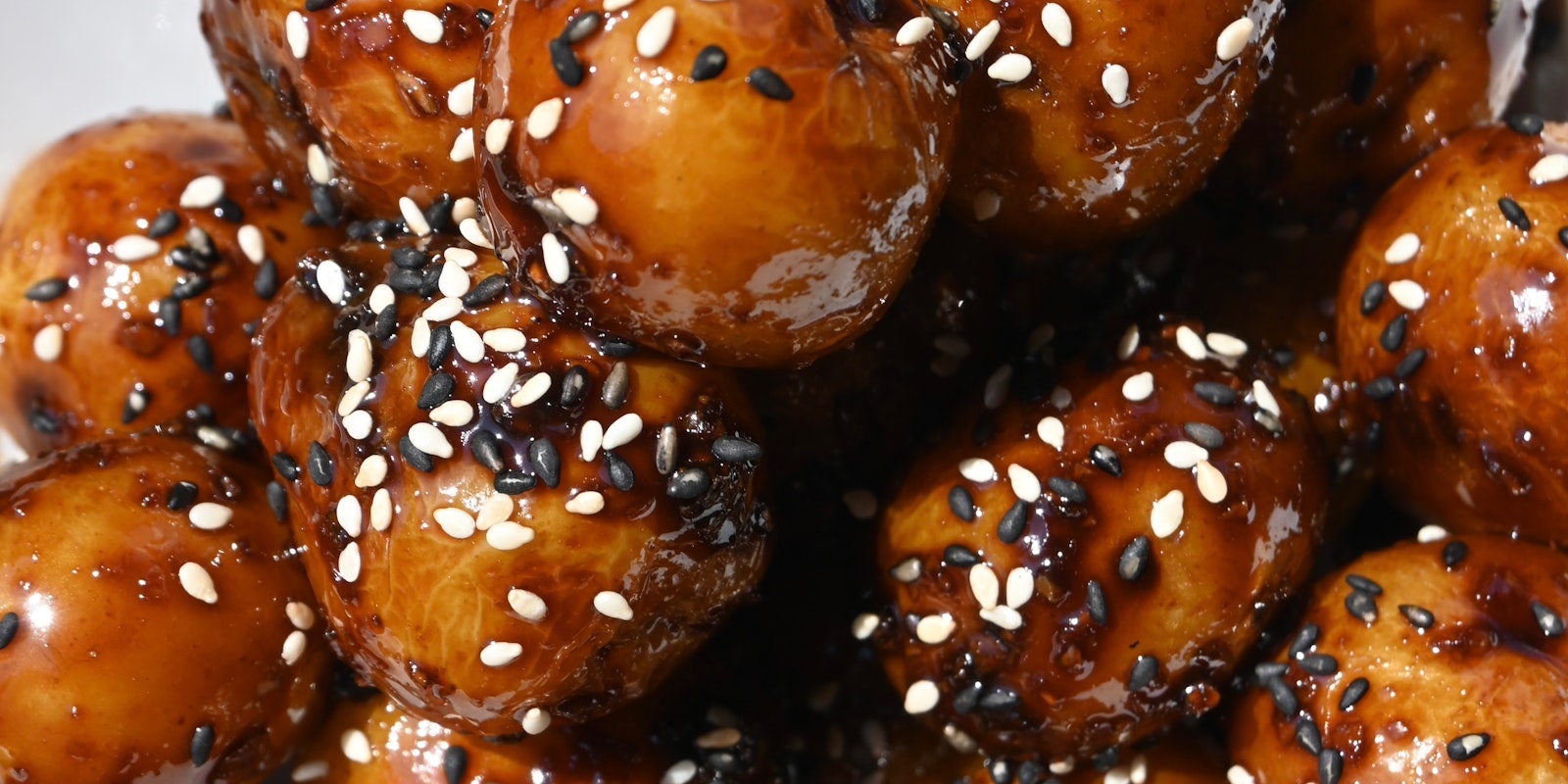 A close up of Korean braised potatoes covered in black and white sesame seeds and made with Little Mini Yellows™ Little Potatoes.