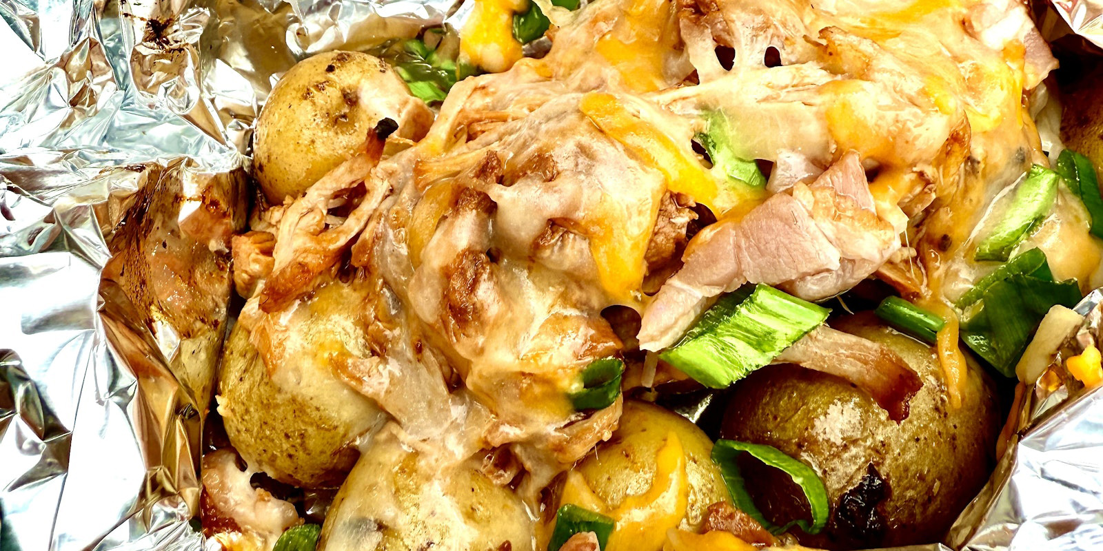 A foil pack full of Little Minis™ topped with pulled pork and shredded cheese.