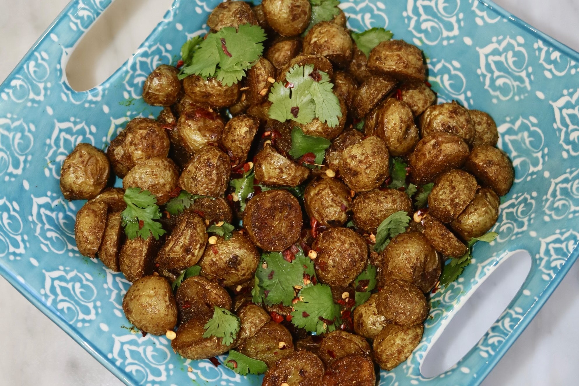 A plate of crispy masala roasted Little Potatoes on a blue plate.