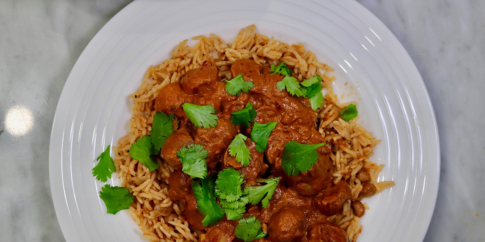 A plate of aloo curry on a white plate.