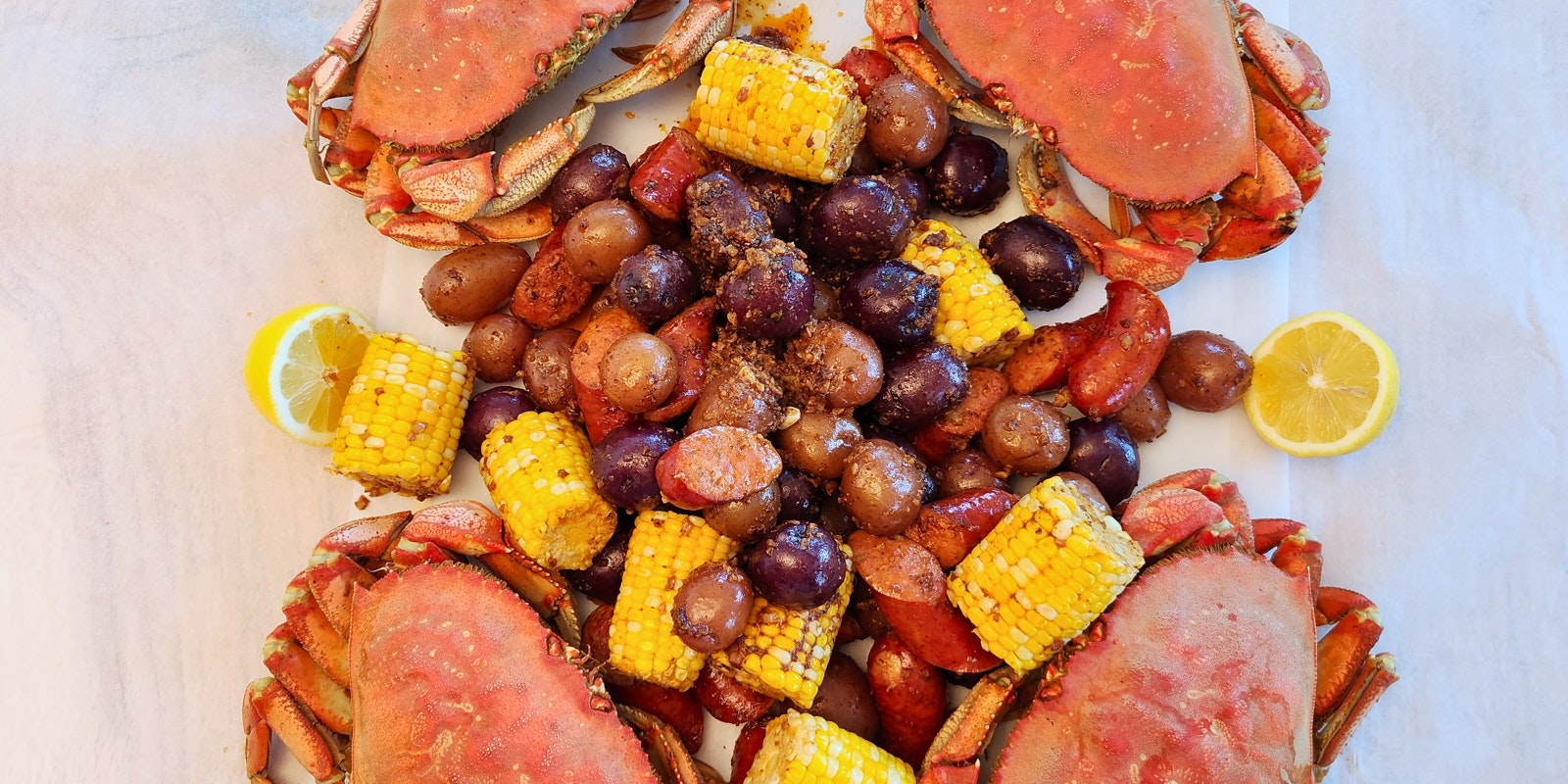 A piece of parchment paper with crabs, corn, and Little Reds™ in a delicious crab boil.